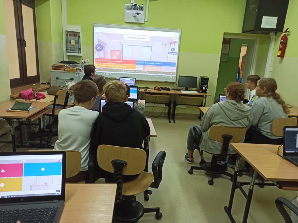 Sala komputerowe. Uczniowie rozwiązują w aplikacji Kahoot! test o Patronie Szkoły.