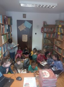 Na zdjęciu widzimy uczniów klasy pierwszej w bibliotece, którzy przeglądają ksiąki.