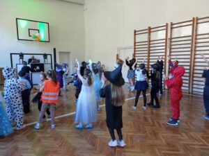 Dzieci z oddziału przedszkolnego i klas I - III tańczą wspólnie w sali gimnastycznej.