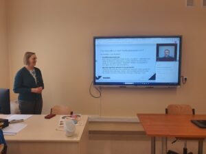 Jedna nauczycielka stoi przy tablicy interaktywnej podczas lekcji online DBI 