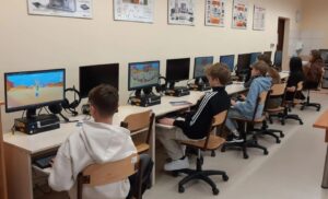 Pięciu uczniów klasy 7 siedzi przy komputerach w sali komputerowej 