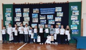 Trzynaścioro dzieci nagrodzonych w konkursie stoi przed galerią pac konkursowych.