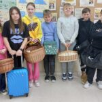 Uczniowie klasy 5 z różnymi nosidłami: kosze, pudełka tekturowe i plastikowe torby i walizy podróżne