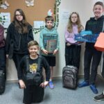Uczniowie klasy 6 z nosidłami: torby i walizy podróżne, worek, pudełko po obuwiu, kosz, skrzynka na owoce.