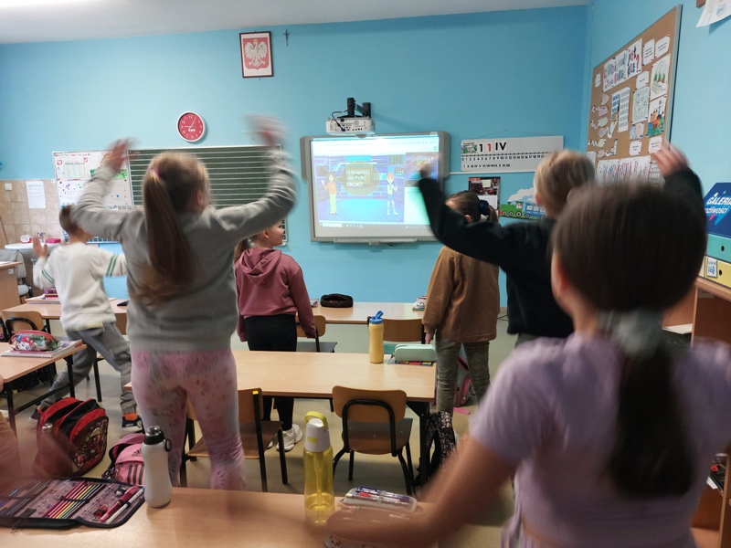 Uczniowie klasy III wykonują polecenia prowadzącego lekcje. Skaczą ci uczniowie, którzy lubią w sieci oglądać filmy.