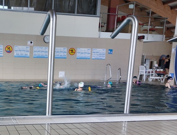 Dziewczynki uczą się pływania pod okiem instruktora.
