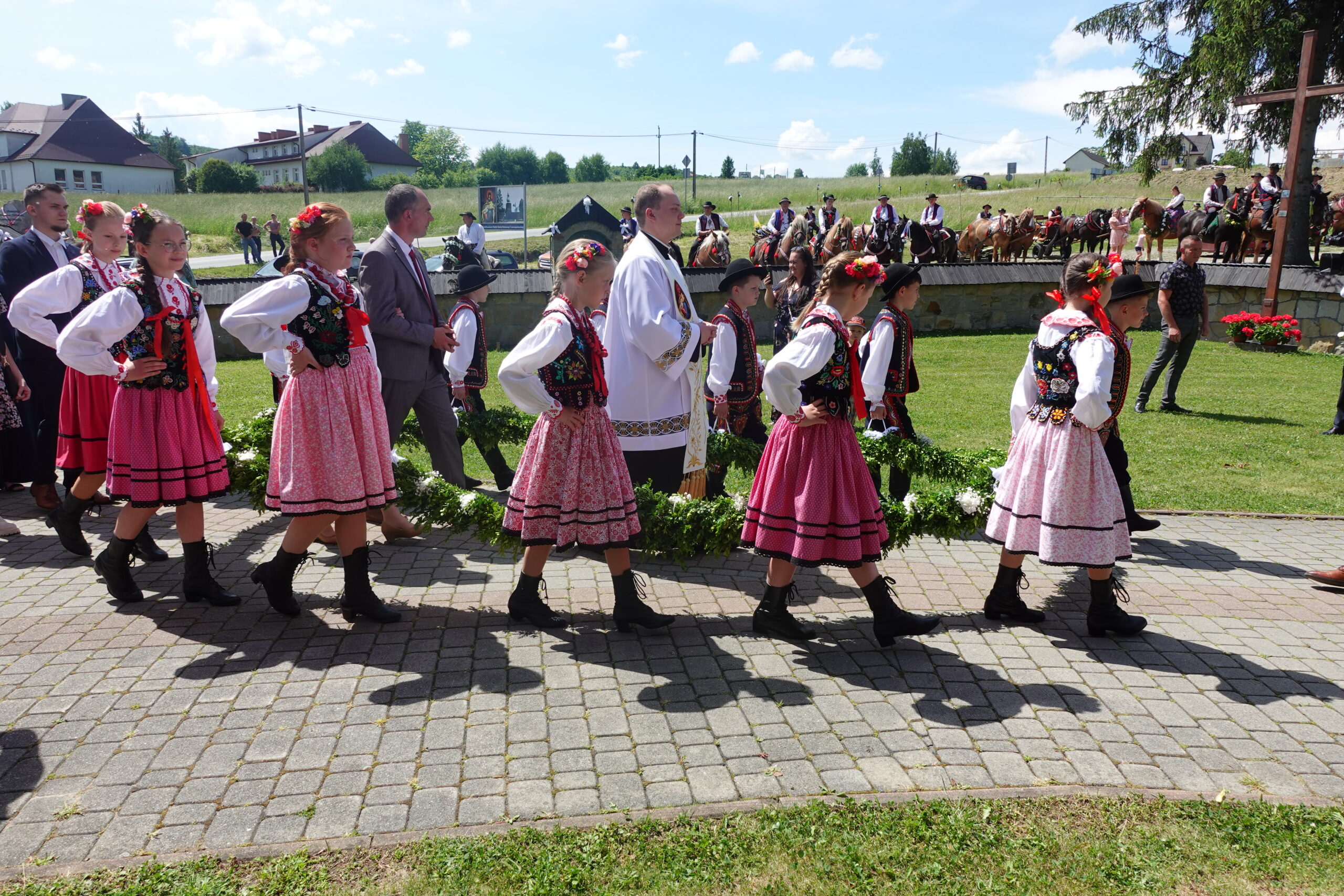 Wprowadzenie Księdza Prymicjanta w wieńcu, który niosą uczniowie - członkowie Zespołu Czarny Potoczek.