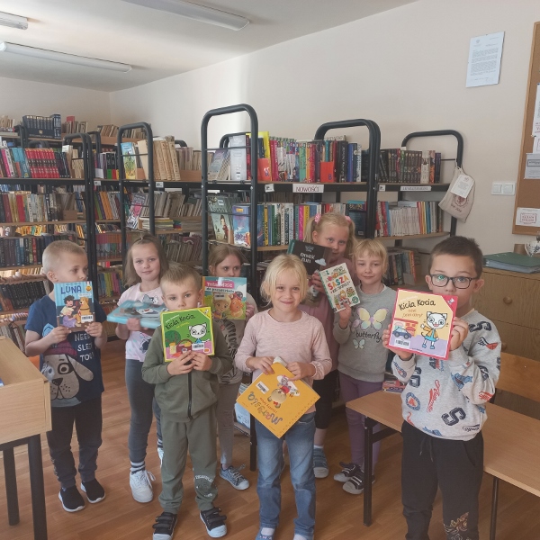 Dzieci w bibliotece szkolnej prezentują, wybrane przez siebie do pożyczenia, książeczki.