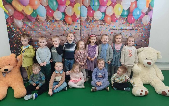 W centralnej części zdjęcia widzimy jedną z grup przedszkolnych, która pięknie się uśmiecha.