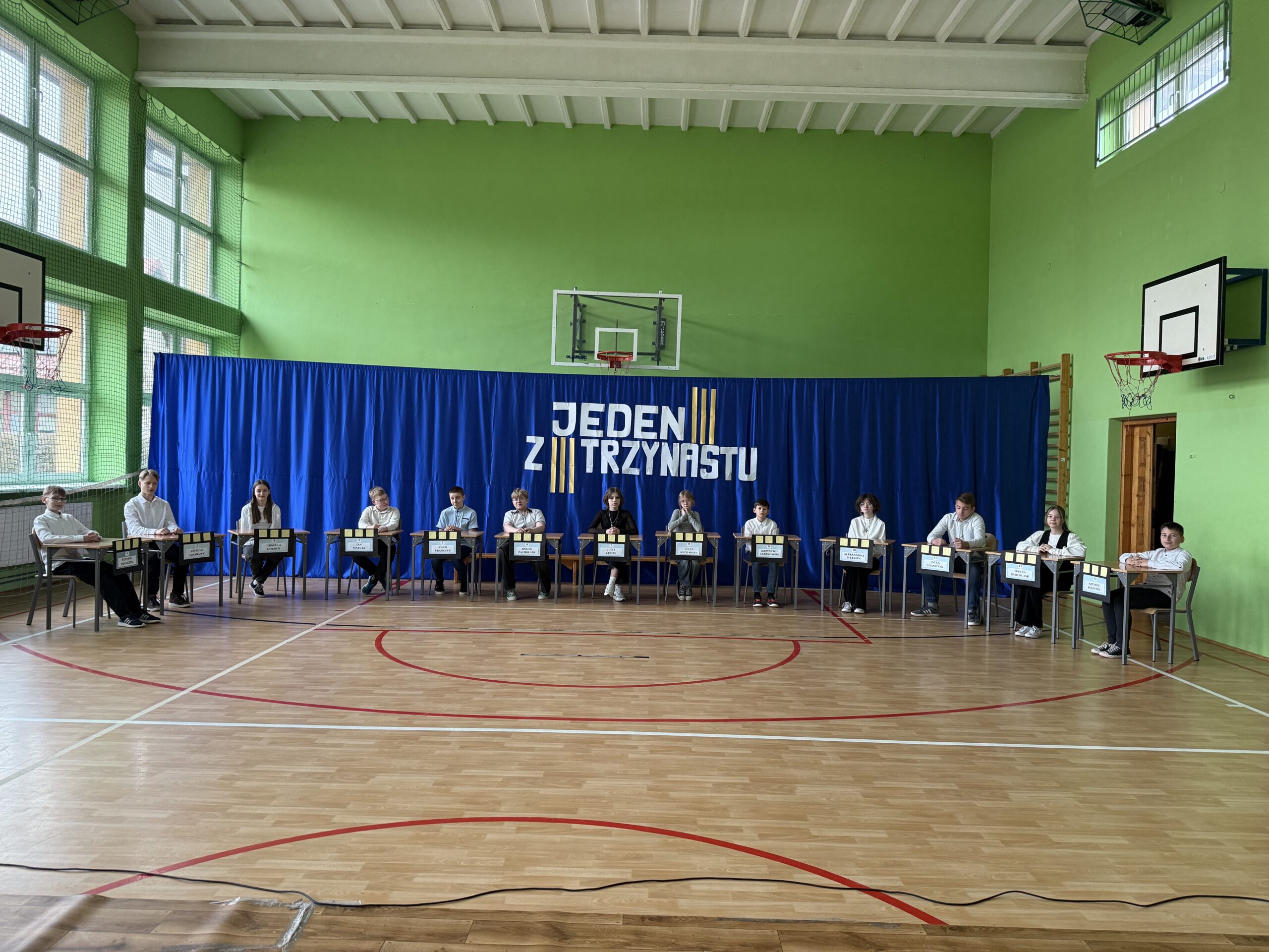 Na zdjęciu jest 13 uczestników którzy siedzą na krzesełkach w półokręgu