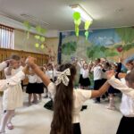 Taniec dzieci w kole - dzieci trzymają się za ręce, ręce maja podniesione do góry