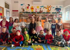 Na pierwszym planie można dostrzec grupę dzieci przebranych w pięknie, bajkowe stroje karnawałowe.
