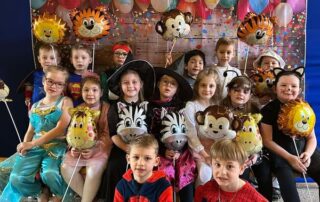 Na zdjęciu widać grupę ,,Sówek'', które uśmiechają się do zdjęcia i trzymają w rękach balony.