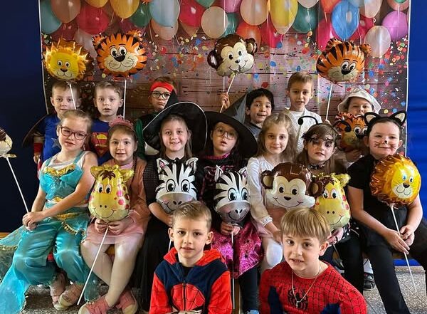 Na zdjęciu widać grupę ,,Sówek'', które uśmiechają się do zdjęcia i trzymają w rękach balony.