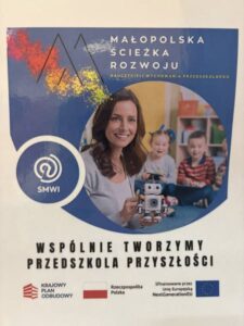 W centralnej części obrazu znajduje się plakat projektu edukacyjnego o nazwie ,,Małopolska Ścieżka Rozwoju Nauczycieli Wychowania Przedszkolnego.''