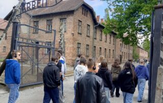 Uczniowie klasy VII i VIII przechodzą przez bramę z napisem „Arbeit macht frei”