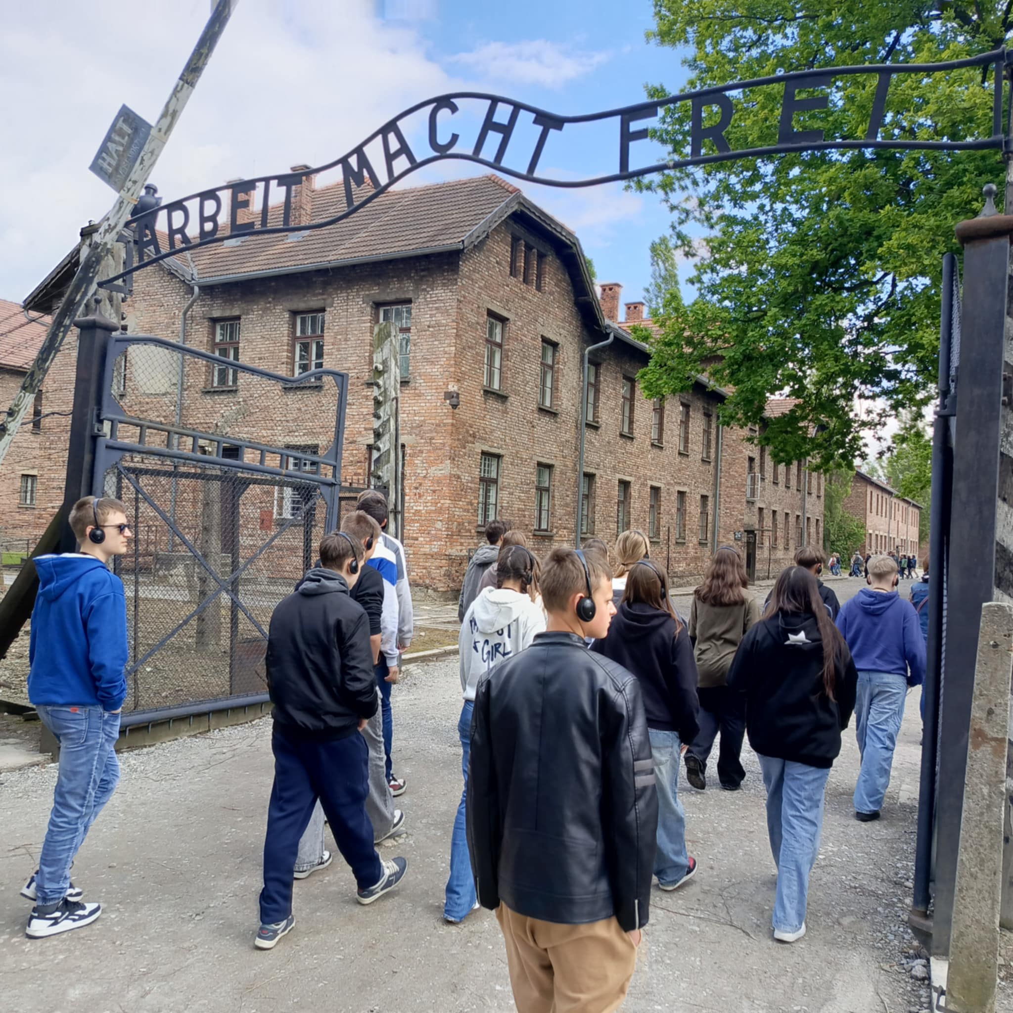 Uczniowie klasy VII i VIII przechodzą przez bramę z napisem „Arbeit macht frei”