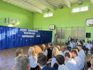 Pani Dyrektor przemawia uczniowie siedzą na ławeczkach