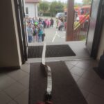 Wąż strażacki przeciągnięty od wozu do szkoły