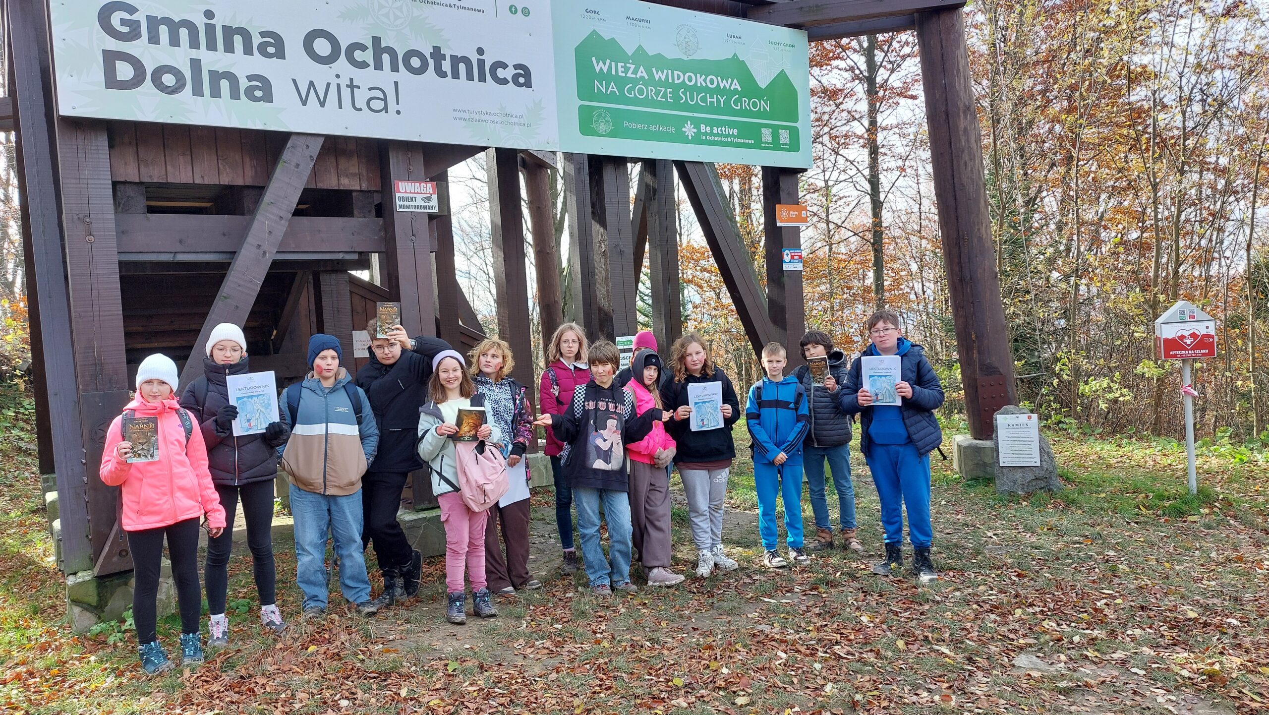 Uczniowie pod wieżą - niektórzy trzymają lektury w dłoniach