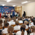 Występ uczniów - trzy uczennice recytują wiersz - zdjęcie zza publiczności