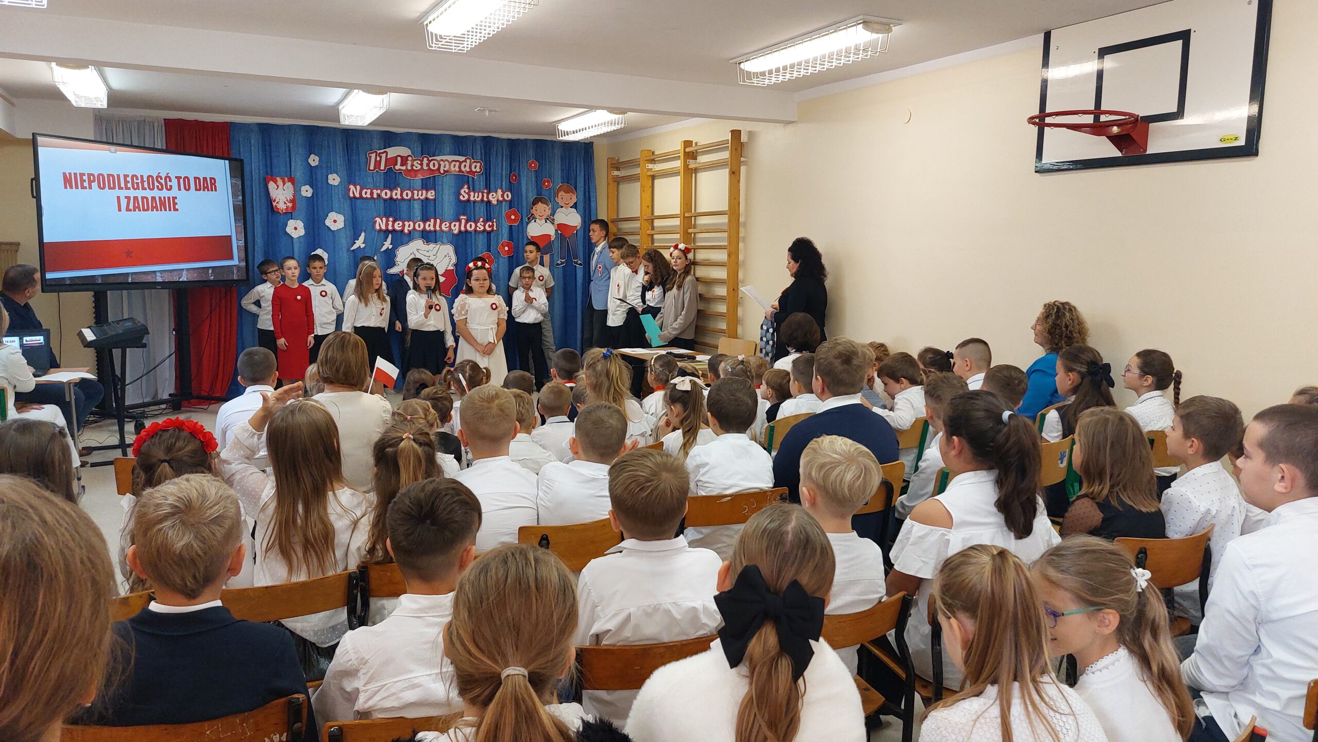 Występ uczniów - trzy uczennice recytują wiersz - zdjęcie zza publiczności