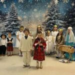 Zdjęcie panoramiczne: dziewczynka i chłopiec w stroju ludowym rozpoczynają jasełka