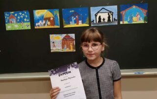 Anastazja z dyplomem na tle prac konkursowych