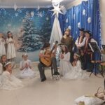 Dziewczynka gra na gitarze w otoczeniu aniołków