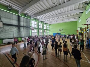 Na zdjęciu widać uśmiechnięte dzieci bawiące się i tańczące na zabawie andrzejkowej.
