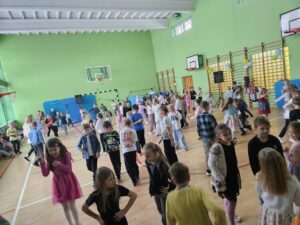 Na zdjęciu widać uśmiechnięte dzieci bawiące się i tańczące na zabawie andrzejkowej.
