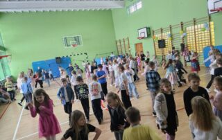 Na zdjęciu widać uśmiechnięte dzieci bawiące się i tańczące na zabawie andrzejkowej.