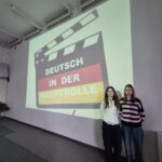 Nasze uczennice pod tablicą, na której wyświetlone jest logo konkursu